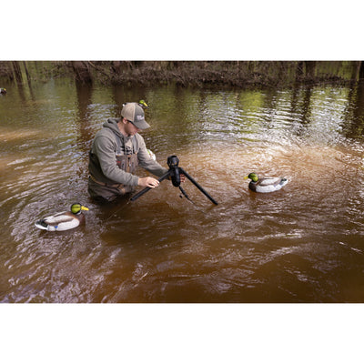 The Higdon Outdoors Motion Machine, a black tripod device with three angled legs and wire attachments, lies on the ground—an ideal water motion tool for boosting your decoy spread—shown against a white background.